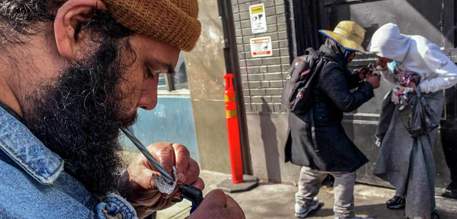 A man smoke from a pipe on public street outside