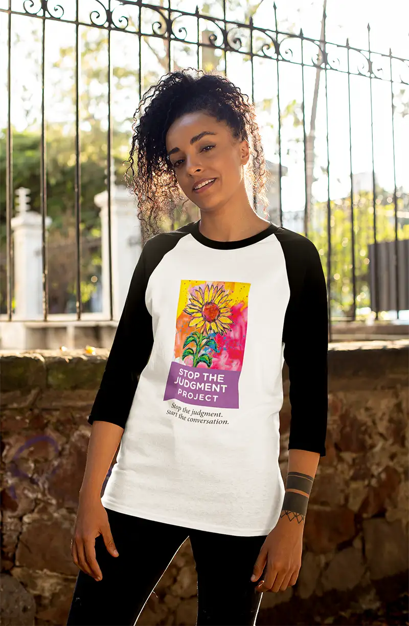 A young woman wearing a Stop The Judgment Project 3/4 sleeve raglan style shirt