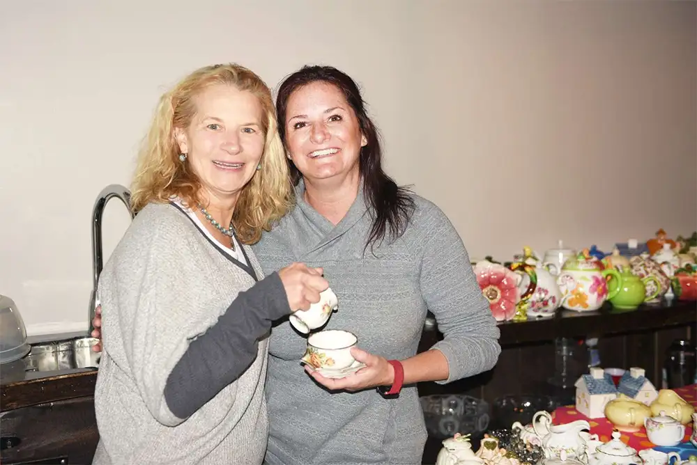 From left, Sherry Jo Matt and Erin McCurdy pose with the collection of tea sets prepared for a tea party at McCurdy's home in Cranberry Township.
